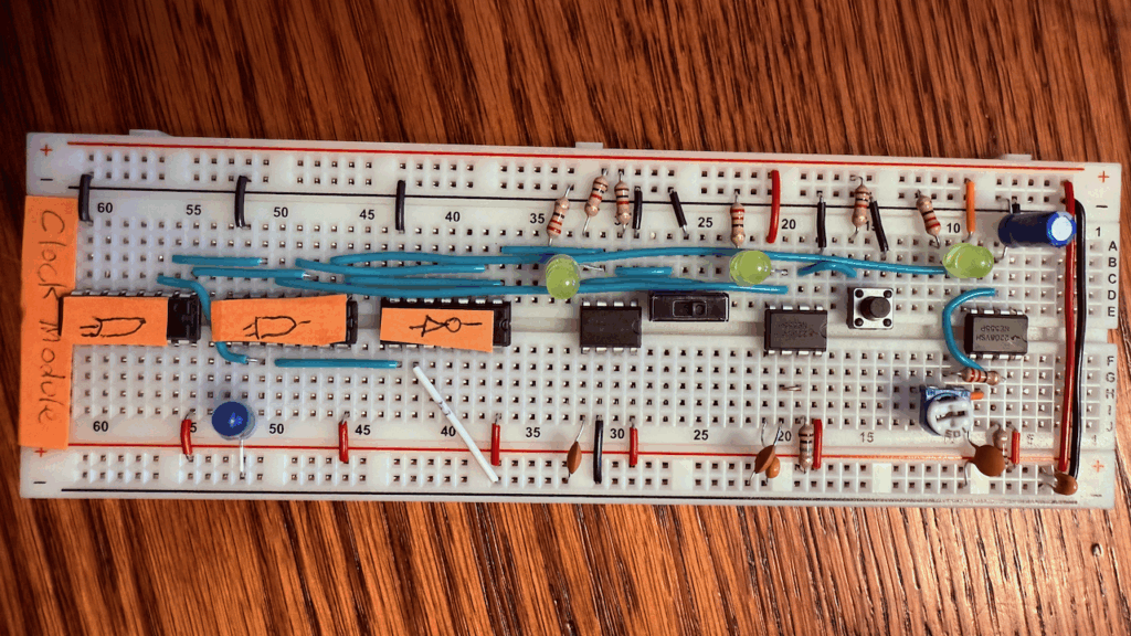 The fully-completed clock module, with labels on the bottom reading "clock module" as well as symbols for OR and AND gates, as well as one for an inverter. There's also a lead tying pin 7 on the inverter to ground, indicating that the clock is not halted.