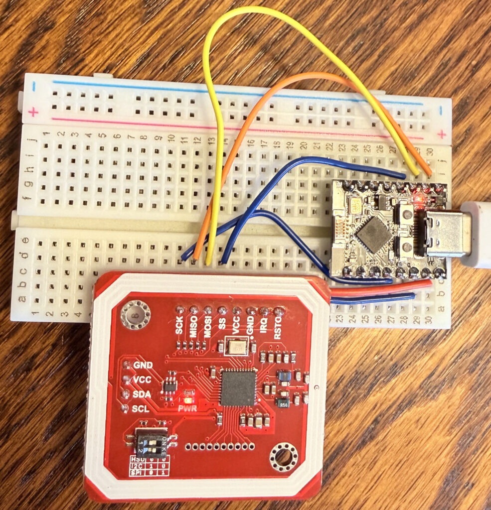 A photograph of an ESP32 C3 Super Mini wired to a red PN532 NFC module breakout board on a short solderless breadboard. The device is configured using an SPI interface.