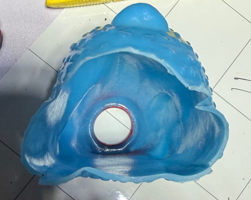 The bottom end of the rubber chicken, feet removed showing the inside of the bellows. There have been four slits cut into the vinyl.