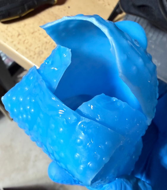 A blue rubber chicken after all cuts were made, with one half of the gluing complete.